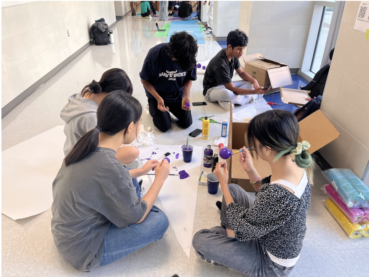 Student volunteers work diligently painting props for the dance. 
